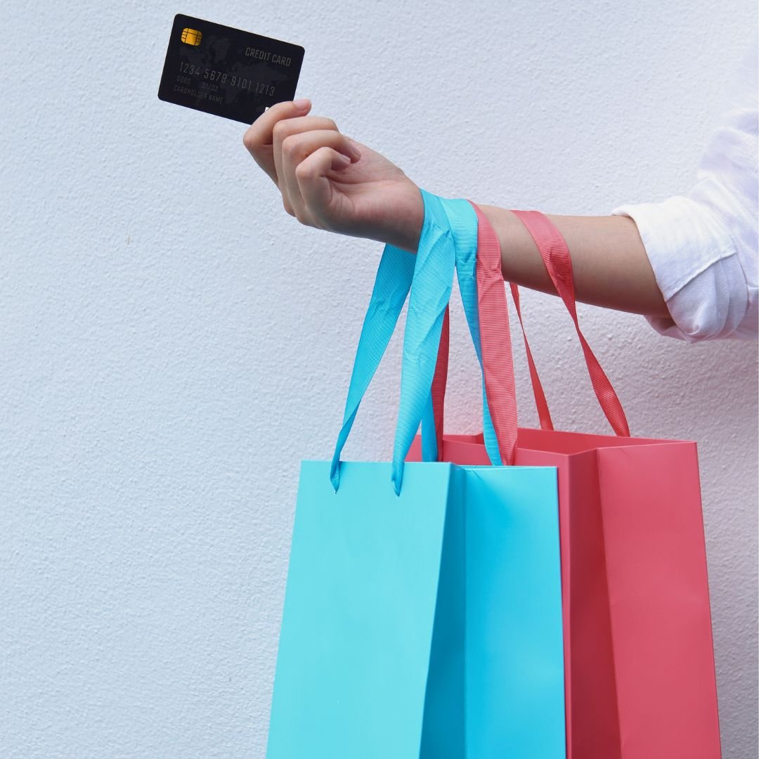 Consumer holding credit card and shopping bags representing debt settlement customer outreach with phone and email appending services for contact recovery