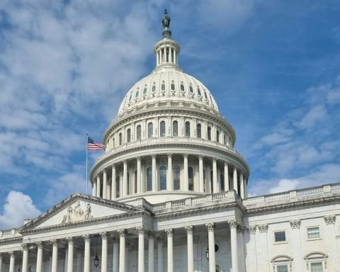 US Capitol building dome with American flag against blue sky in Washington DC