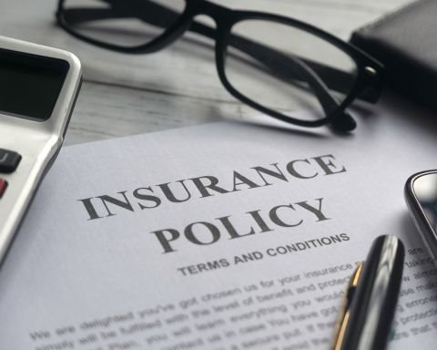 Insurance policy document with terms and conditions on desk with eyeglasses and pen