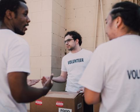 Diverse volunteer team in white volunteer shirts packing food donation boxes for community service