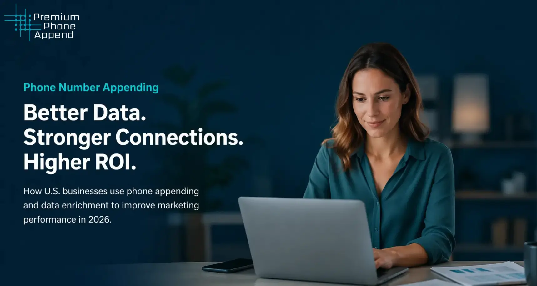 Woman working on laptop at desk reviewing phone appending and data enrichment strategies for marketing